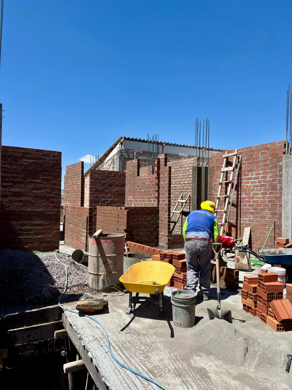 Ouvrier sur un chantier, devant des murs en briques en construction